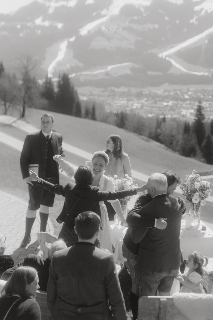 Gäste bei der Trauung mit Blick auf die Kitzbüheler Alpen – sonnige Hochzeitszeremonie im Freien

